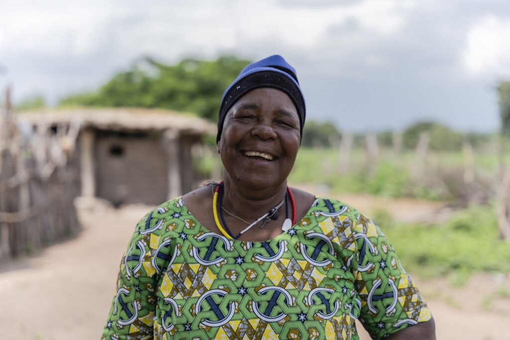 Cataract patient Holo smiles while standing outside her home. Holo's story shows the importance of universal health coverage. 